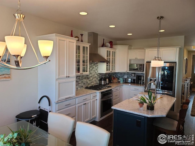 kitchen featuring stainless steel appliances, wall chimney exhaust hood, white cabinetry, and decorative backsplash