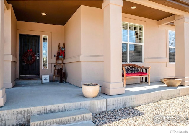 entrance to property with a porch and stucco siding