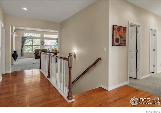 staircase featuring baseboards, carpet flooring, wood finished floors, and recessed lighting