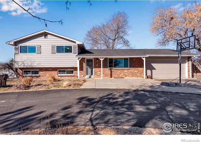 tri-level home featuring a garage, concrete driveway, and brick siding