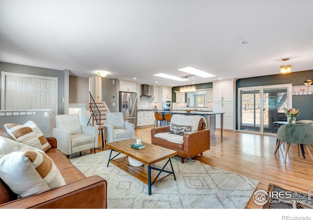 living room with light wood-type flooring, a skylight, stairway, and recessed lighting