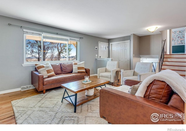 living area featuring baseboards, stairs, visible vents, and wood finished floors