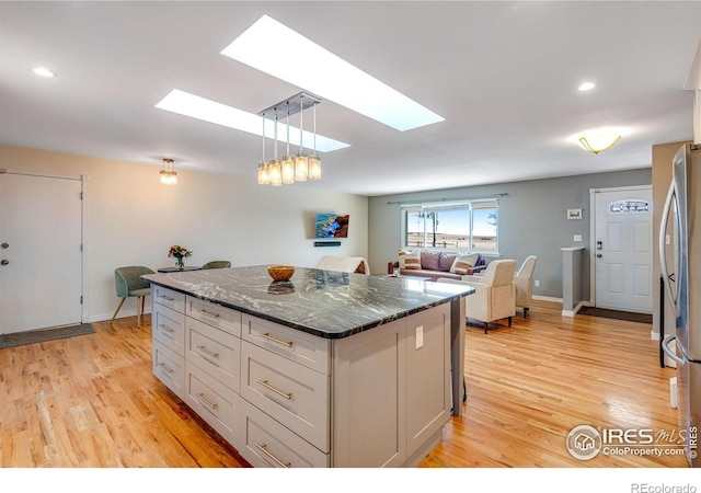 kitchen with a kitchen island, white cabinets, open floor plan, freestanding refrigerator, and light wood finished floors