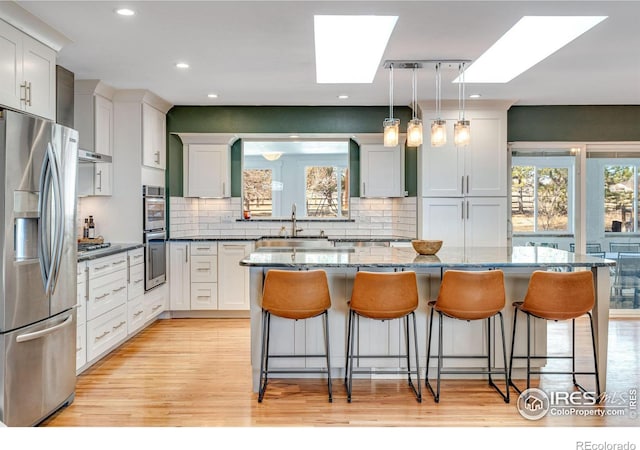 kitchen featuring appliances with stainless steel finishes, a skylight, a sink, and a healthy amount of sunlight