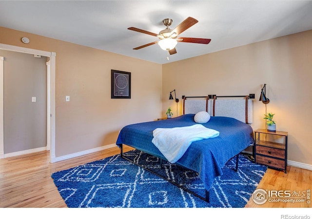 bedroom with ceiling fan, wood finished floors, and baseboards