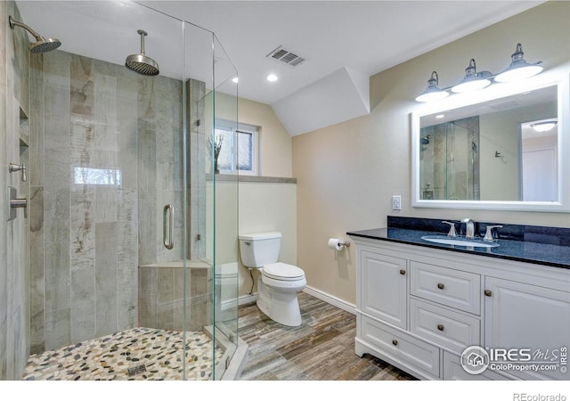 full bath with toilet, wood finished floors, vanity, visible vents, and a shower stall