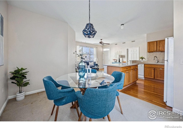 dining area with light carpet, light wood finished floors, and baseboards