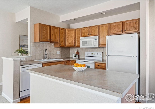 kitchen featuring white appliances, tasteful backsplash, brown cabinets, and a sink