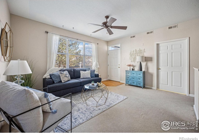 carpeted living area featuring a ceiling fan, visible vents, and baseboards