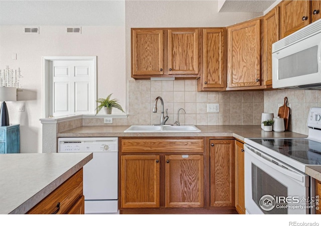 kitchen with tasteful backsplash, white appliances, visible vents, and a sink