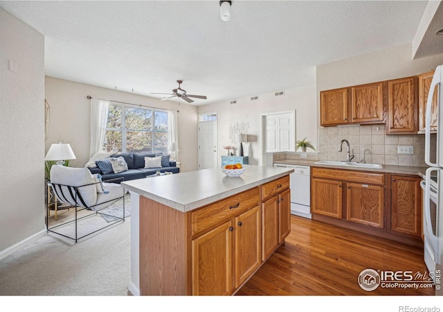 kitchen featuring a center island, tasteful backsplash, light countertops, a sink, and dishwasher