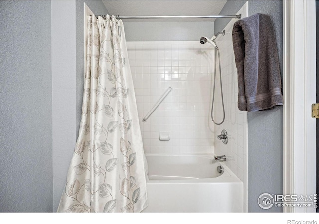 bathroom featuring shower / bath combo and a textured wall