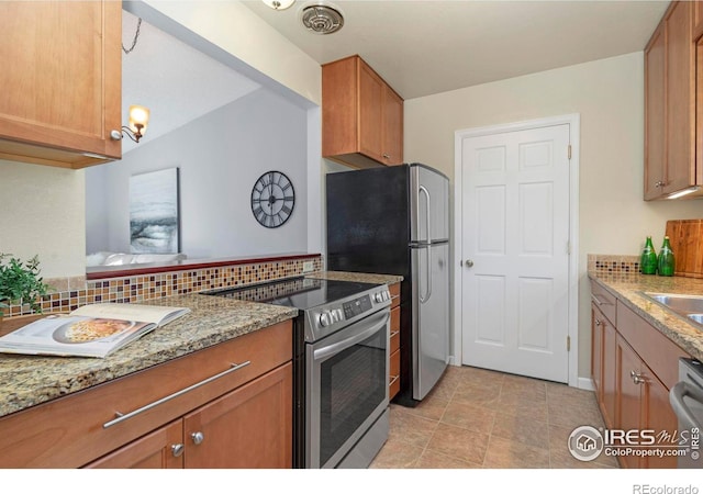 kitchen with electric stove, tasteful backsplash, brown cabinetry, and light stone countertops