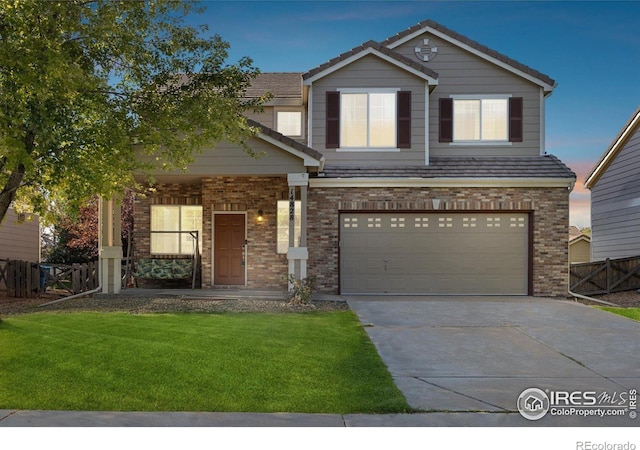 view of front facade with brick siding, an attached garage, fence, driveway, and a front lawn