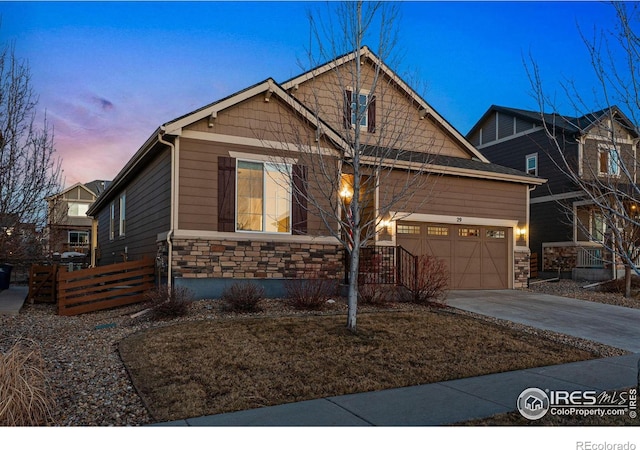 craftsman house featuring stone siding, an attached garage, fence, and driveway