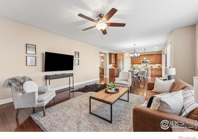 living room with dark wood-style floors, recessed lighting, baseboards, and ceiling fan with notable chandelier