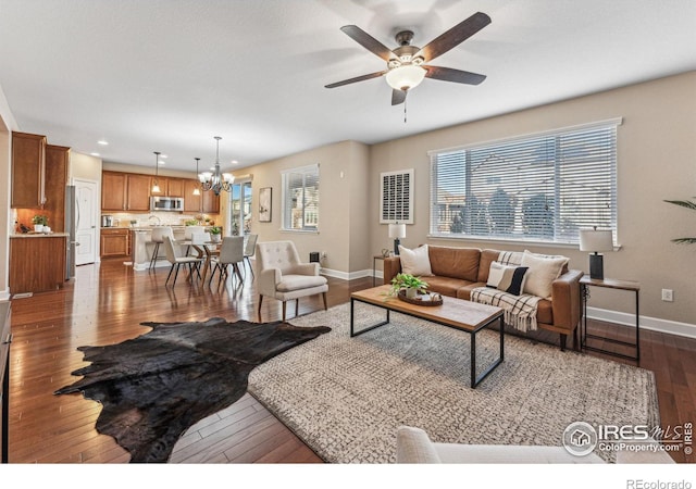 living area featuring ceiling fan with notable chandelier, dark wood-style flooring, recessed lighting, and baseboards