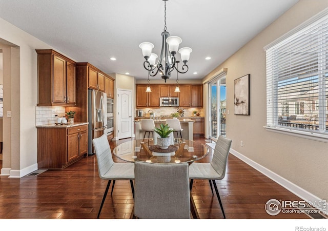 dining space featuring a chandelier, dark wood-style flooring, and baseboards