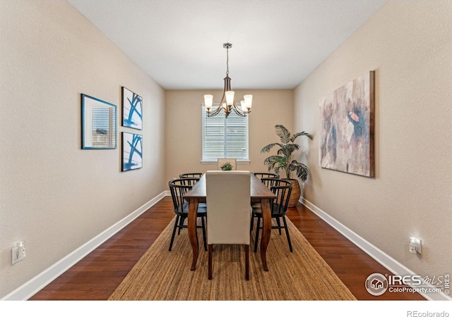 dining space featuring a chandelier, dark wood-type flooring, and baseboards