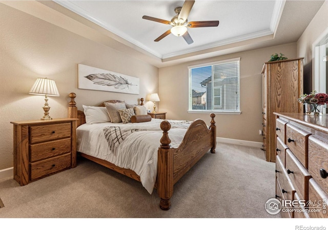 bedroom with light carpet, baseboards, a tray ceiling, and crown molding