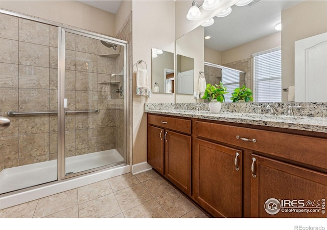 full bathroom with double vanity, a stall shower, tile patterned flooring, and a sink