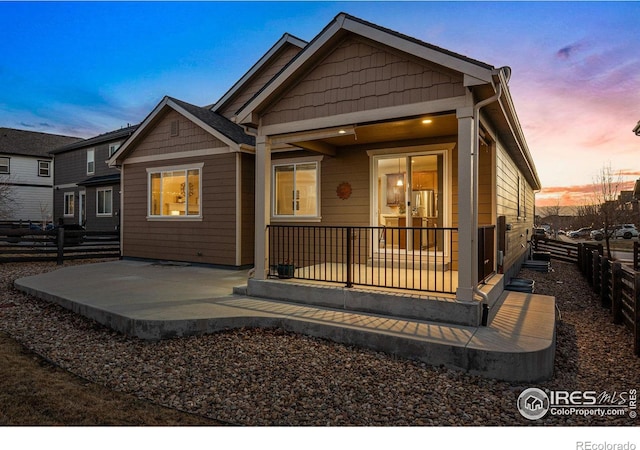 back of property at dusk with a patio and fence