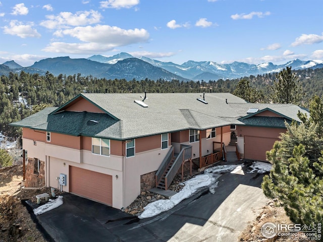 view of front of house with roof with shingles, a mountain view, driveway, and stucco siding