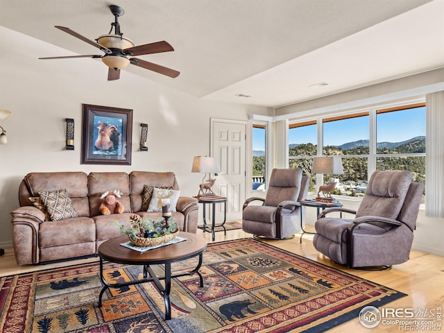 living area with a mountain view, visible vents, wood finished floors, and a wealth of natural light