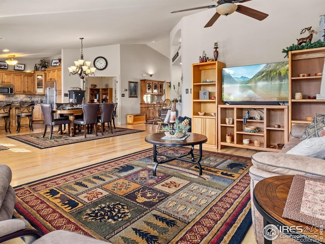 living room featuring ceiling fan with notable chandelier, lofted ceiling, and wood finished floors