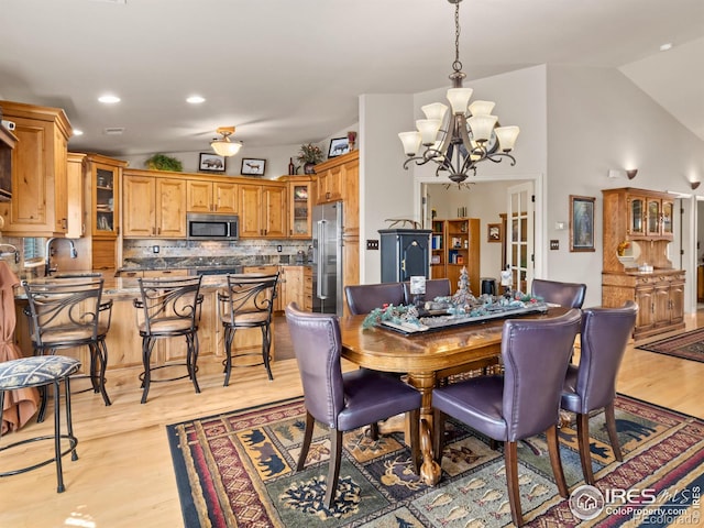 dining area with lofted ceiling, light wood-style floors, a notable chandelier, and recessed lighting