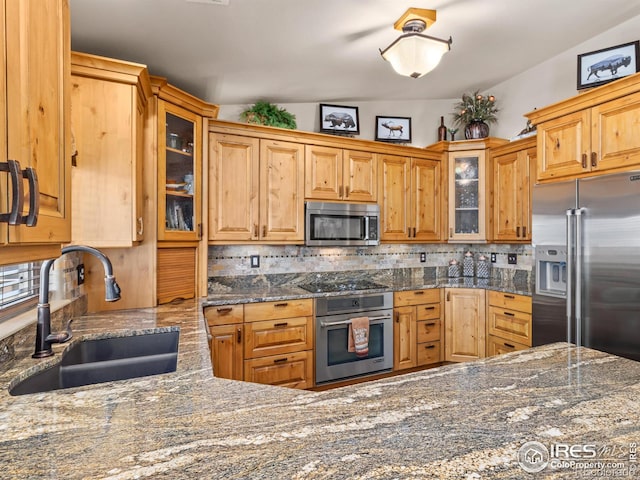 kitchen with stainless steel appliances, glass insert cabinets, a sink, and backsplash