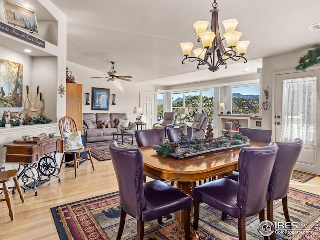 dining area with ceiling fan with notable chandelier and wood finished floors