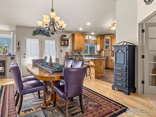 dining area featuring recessed lighting, a fireplace, light wood-style flooring, and an inviting chandelier