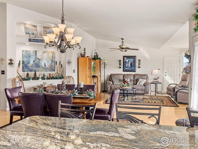 dining area with vaulted ceiling, wood finished floors, and ceiling fan with notable chandelier