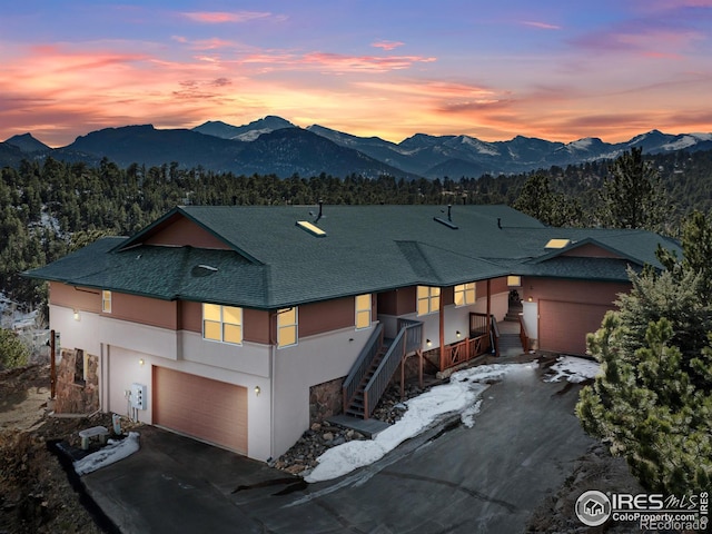 view of front of house featuring driveway, roof with shingles, a mountain view, and stucco siding