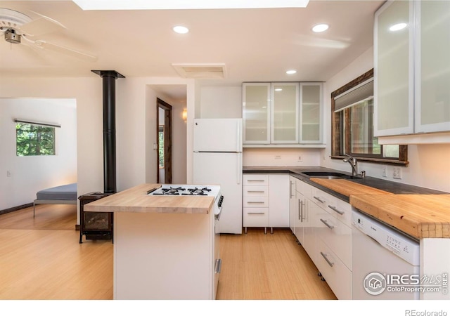 kitchen with a center island, wooden counters, a sink, light wood-type flooring, and white appliances