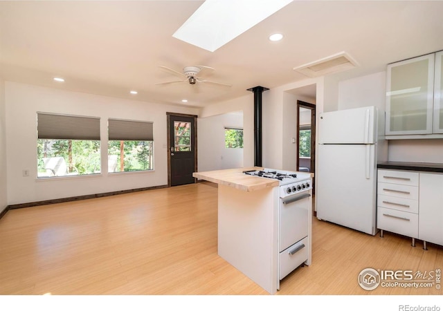 kitchen featuring white appliances, glass insert cabinets, a center island, light wood-style floors, and recessed lighting