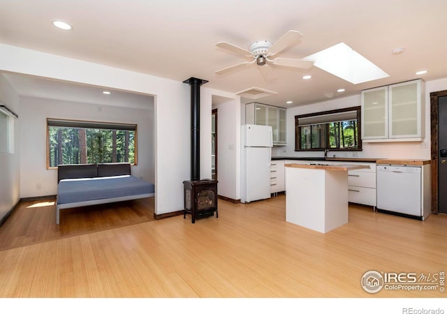 kitchen with white appliances, glass insert cabinets, light wood-style floors, white cabinetry, and a sink