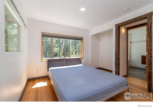 bedroom featuring a closet, recessed lighting, wood finished floors, and baseboards