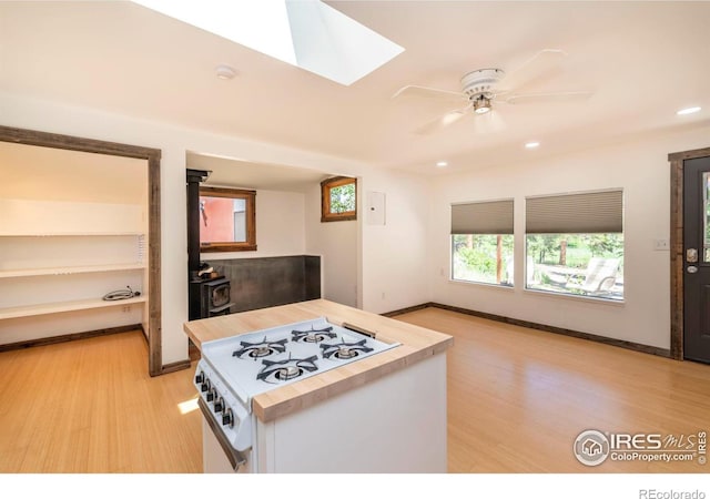 kitchen with ceiling fan, white gas stove, open floor plan, light wood-type flooring, and a wood stove