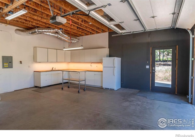 garage featuring electric panel, a garage door opener, and freestanding refrigerator