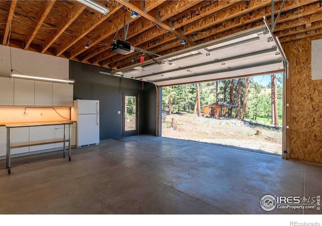 garage with a garage door opener and freestanding refrigerator