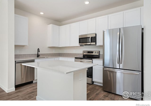 kitchen featuring appliances with stainless steel finishes, dark wood finished floors, white cabinetry, and a sink