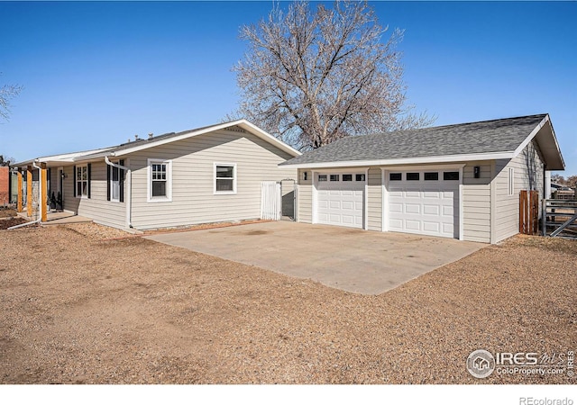 exterior space featuring a garage, roof with shingles, an outdoor structure, and fence