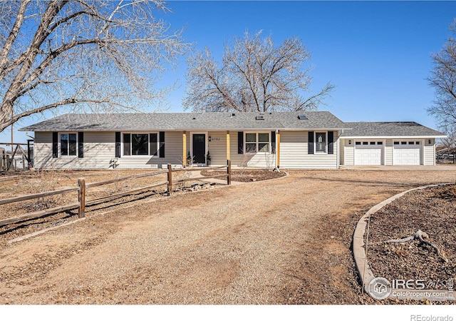 ranch-style house featuring a garage, dirt driveway, and fence