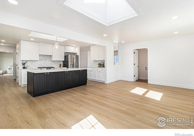 kitchen with light wood-style flooring, white cabinetry, light countertops, stainless steel refrigerator with ice dispenser, and decorative backsplash