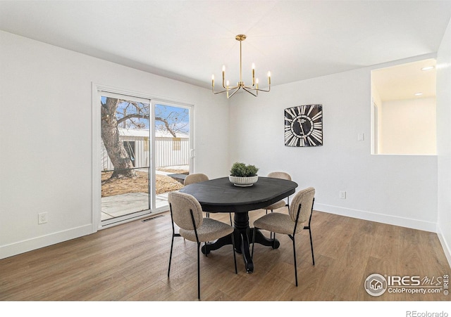 dining room featuring an inviting chandelier, visible vents, baseboards, and wood finished floors