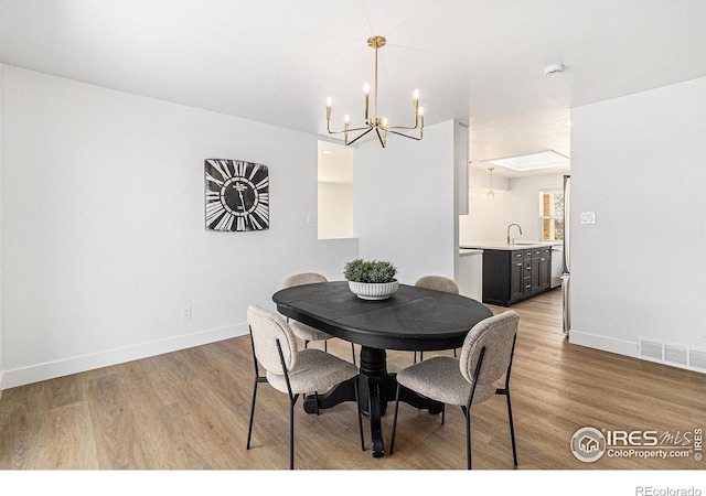 dining area with an inviting chandelier, visible vents, baseboards, and wood finished floors