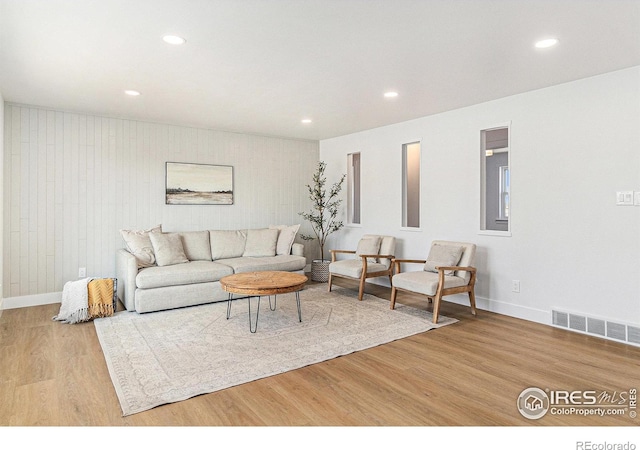 living room with recessed lighting, visible vents, baseboards, and wood finished floors