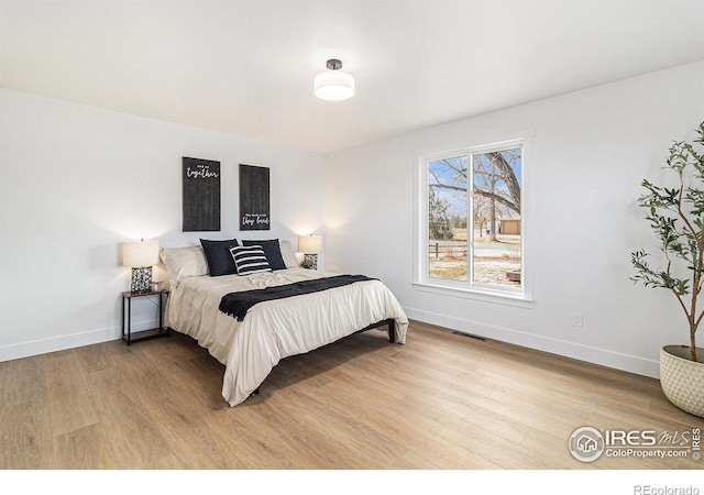 bedroom with light wood-style flooring, visible vents, and baseboards